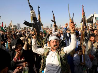 Combatientes hutíes blanden sus armas durante una protesta tras los ataques del viernes.