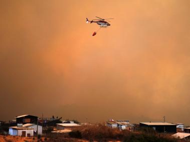 Un helicóptero trabaja en la zona de un incendio forestal en los cerros de la comuna de Quilpe, región de Valparaíso.