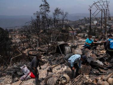 Personas retiran escombros desde una casa en el sector de Achupallas afectada por incendios forestales de Viña del Mar.