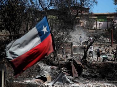 Una bandera chilena ondea cerca a las casas quemadas en Villa Independencia, región de Valparaíso, Chile.
