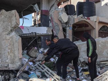 Palestinos buscan sobrevivientes y cuerpos entre los escombros de un edificio tras los bombardeos israelíes en Rafah, sur de Gaza.