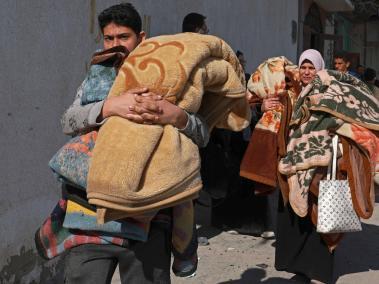 Palestinos huyen de sus casas junto con sus pertenencias tras un bombardeo israelí en Rafah.