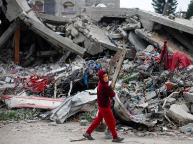 Un niño palestino pasa junto a los escombros de un edificio del campo de refugiados palestinos de Maghazi.