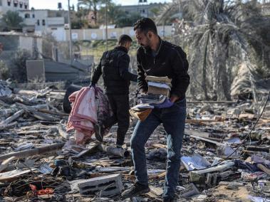 Palestinos buscan sus pertenencias en medio de los escombros de un edificio destruido.