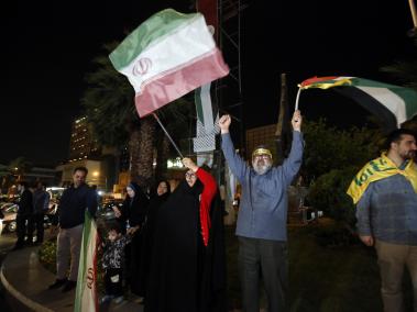 Los iraníes ondean una bandera iraní y una palestina durante una manifestación antiisraelí después de que Irán lanzara ataques con drones contra Israel en la Plaza Palestina de Teherán, Irán.