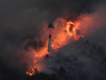 Un helicóptero transporta un extintor en la lucha contra un incendio que se extendió cerca de Vitrolles, sur de Francia. El incidente hizo que el cielo de Marsella se llenara de humo.
