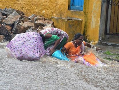 En Hyderabad, India, dos mujeres se deslizan en una calle inundada debido a las fuertes lluvias que se presentan en la región.