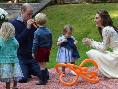 El príncipe William infla un globo mientras él y su esposa Kate, la duquesa de Cambridge, participan en una fiesta de té con sus hijos.