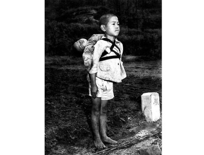Un niño en Nagasaki (Japón) espera para cremar el cuerpo de su pequeño hermano tras los desastres de la bomba atómica de 1945.