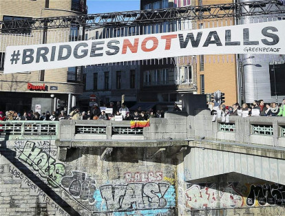 Una pancarta de Greenpeace que reza "puentes, no muros" encabeza una protesta contra el presidente electo de los Estados unidos, Donald Trump, en el puente Molenbeek en Bruselas.