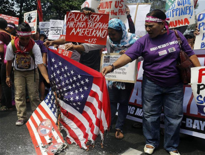 Varios manifestantes queman una bandera estadounidense mientras se manifiestan frente a la embajada de Estados Unidos en Manila contra la llegada de Donald Trump a la Casa Blanca.
