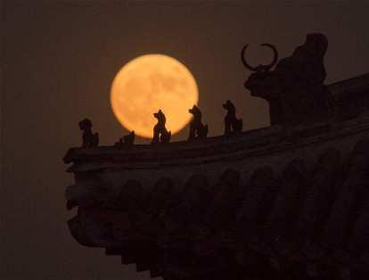 La superluna asciende sobre una serie de esculturas en algún punto de Beijing, en China.
