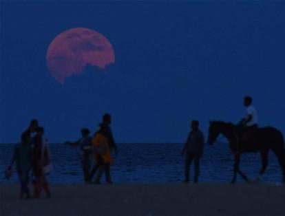 La luna acompañó a estos paseantes de una playa en Chennai, en el sur de la India.