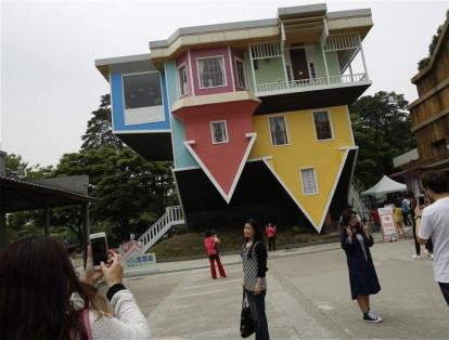 Los visitantes posan frente a una casa invertida de tres pisos en el Parque Creativo de Huashan en Taipei, Taiwán. Su elaboración tuvo un costo de US$ 600.000 y tardó dos meses en ser construída.