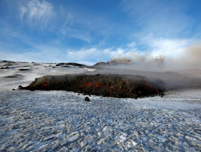En la imagen, un fotógrafo capta con su cámara una imagen del volcán siciliano Etna, en erupción.