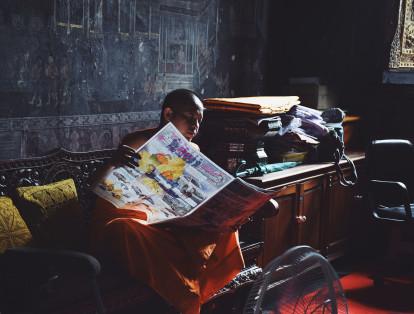 Un monje lee el periódico local durante su tiempo libre entre meditaciones. Bangkok, Tailandia.