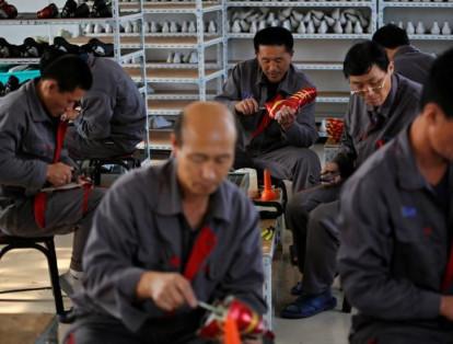 Implementos deportivos, como los guayos, también comparten fabricación en máquinas y operarios. En la foto algunos hombres ensamblan las piezas finales de los zapatos.