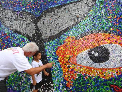 El artista brasileño Ubiratan Fernandes, realizó un mural con más de 30 mil tapas recicladas. Pide protejer de basuras a los ríos y mares.