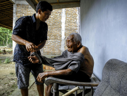 Suryanto, de 47 años, cuida de su abuelo Sodimejo en su hogar en Sragen (Indonesia).