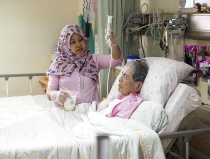 Una cuidadora indonesia  alimenta por sonda a una anciana taiwanesa en un hospital de Taipei (Taiwán).