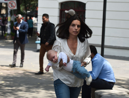 Una madre carga a su hijo en brazos en medio de la confusión.