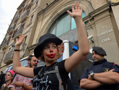 Una manifestante levanta sus brazos junto a un oficial de la Policía catalana a las afueras de los cuarteles de la Guardia Civil durante una protesta.