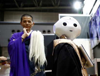 Un monje budista observa a un "sacerdote robot" vestido con una túnica budista durante su demostración en la Exposición de la industria de la vida final 2017 en Tokio, Japón.