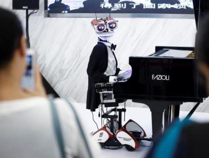 La gente mira el robot "Teo Tronico", diseñado por Matteo Suzzi, toca el piano y canta canciones populares en la Conferencia Mundial de Robots 2017 en Beijing, China.