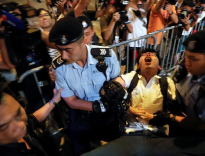 El líder de una protesta estudiantil Joshua Wong grita mientras los manifestantes son arrestados en un monumento que simboliza el traspaso de la ciudad del dominio británico al chino, un día antes de que el presidente chino, Xi Jinping, llegara a las celebraciones en Hong Kong, China el 28 de junio.