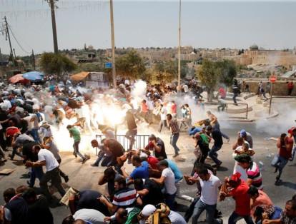 Los palestinos reaccionan cuando las fuerzas israelíes dispararon gases lacrimógenos después de la oración del viernes en una calle a las afueras de Jerusalén, el 21 de julio de 2017.