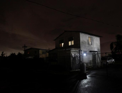 Una casa iluminada con la ayuda de un generador junto a casas en la oscuridad en Dorado, Puerto Rico.