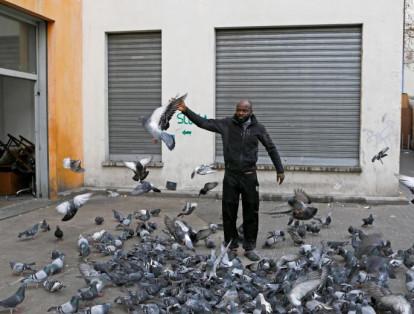 11-	Un hombre alimenta a las palomas, que se conglomeran en las inmediaciones de uno de los edificios de la antigua villa olímpica.