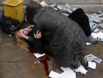 Esta fotografía recuerda el atentado que hizo Khalid Masood cuando condujo su automovil en el Puente de Westminster en Londres, Reino Unido, el 22 de marzo de 2017. En esta imagen Toby Melville captura a un transeúnte que consola a una mujer que yace en la acera tras el atentado.