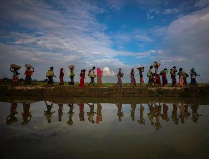 Los refugiados rohinyás se reflejan en el agua de lluvia a lo largo de un terraplén junto a los arrozales después de huir de Myanmar a Palang Khali, cerca de Cox's Bazar, Bangladesh.
