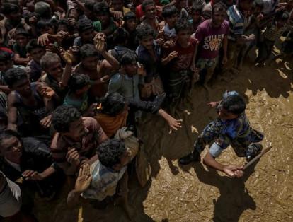 Un oficial de seguridad intenta controlar a los refugiados rohinyás que esperan recibir ayuda en Cox's Bazar.
