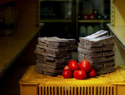 Un kilo de tomates junto a 5'000.000 de bolívares (0,76 dólares) en fajos de billetes, su costo comercial.