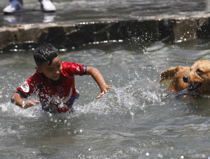 Personas y mascotas disfrutan de las fuente de agua pública