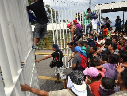 Tras empujar repetidas veces, los migrantes lograron abrir una reja en el puente fronterizo que cruza el río Suchiate.