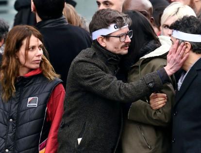 En esta foto tomada el 11 de enero de 2015, los sobrevivientes del ataque observan cómo Renald Luzier toca la mejilla del editorialista Patrick Pelloux, mientras participan en un mitin en París en homenaje a las víctimas de la matanza.