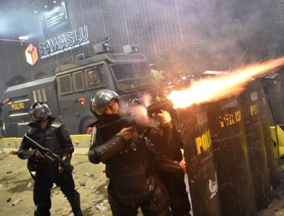 Policías antidisturbios disparan gas lacrimógeno para dispersar a los manifestantes durante las marchas contra el reelegido presidente de Indonesia, Joko Widodo, en Yakarta.