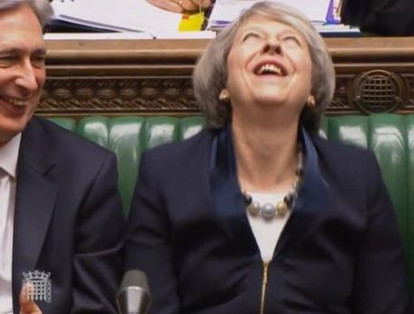 Theresa May se ríe ante una sesión del Parlamento.