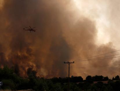 Un helicóptero de extinción de incendios apaga un incendio forestal en el área de Varybobi, suburbio al noreste de Atenas, Grecia.
