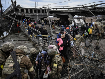 La gente cruza un puente destruido mientras evacuan la ciudad de Irpin, al noroeste de Kiev, durante fuertes bombardeos y bombardeos el 5 de marzo de 2022, 10 días después de que Rusia lanzara una invasión militar en Ucrania.