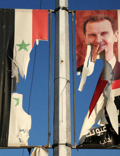 Una valla publicitaria con la imagen del presidente sirio Bashar al-Assad y una bandera nacional son arrancadas por combatientes antigubernamentales en Alepo.