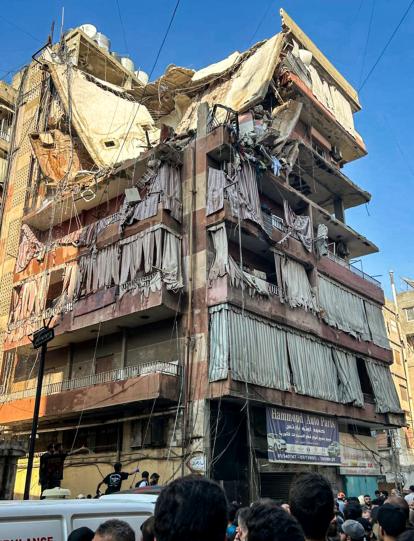 People stand outside a residential building whose top two floors were hit by an Israeli strike in the Ghobeiri area of Beirut's southern suburbs on September 24, 2024. A Lebanese security source said on September 24 that an Israeli strike hit Hezbollah's south Beirut stronghold, as the Israel army confirmed it carried out the strike in the Lebanese capital without giving further details. (Photo by Anwar AMRO / AFP)