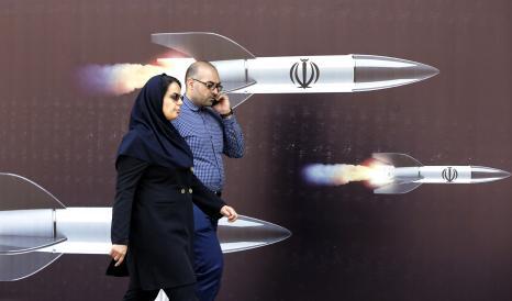 Iraníes pasan junto a una enorme pancarta antiisraelí con imágenes de misiles, en Teherán.