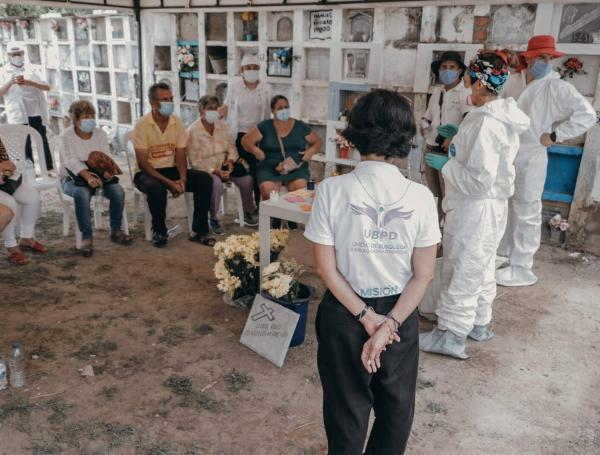 Familiares de víctimas de desaparición forzada y funcionarios de la Unidad de Búsqueda de Personas dadas por Desaparecidas, durante una entrega digna de cuerpos en un cementerio.