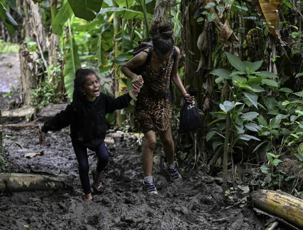 Migrante venezolana ayuda a su hija mientras cruzan la selva del Darién