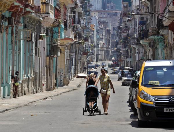 Una mujer camina hoy con un coche para niño por una calle de la Habana.