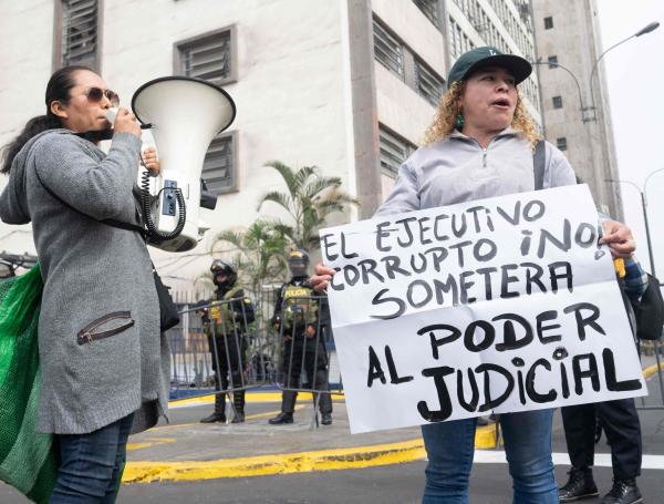 Opositores de la presidenta peruana Dina Boluarte sostienen carteles y gritan mientras ella comparece ante la Fiscalía Nacional en Lima.
